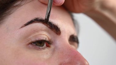Beyaz kadın kaş boyama prosedürü uyguluyor.