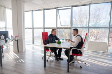 İki beyaz adam bir iş toplantısında iletişim kuruyor.