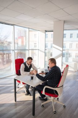 Masada otururken akıllı telefon kullanan iki beyaz adam.