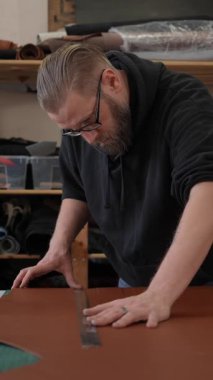 Beyaz sakallı adam bir atölyede bronzlaştırıcı olarak çalışıyor.