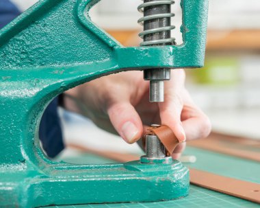 Bir kadın deri kemere aksesuar takar. Deri işçileri atölyesi