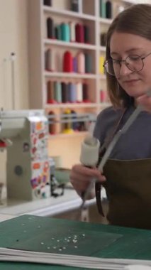 Bir kadın atölyede deri kemerde delikler açıyor.