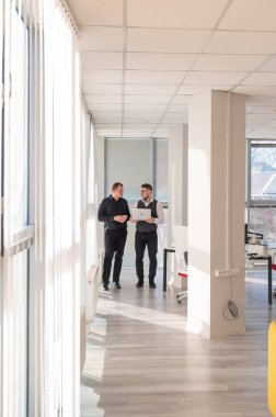 İki beyaz adam dizüstü bilgisayara bakıyor ve iş tartışıyorlar.