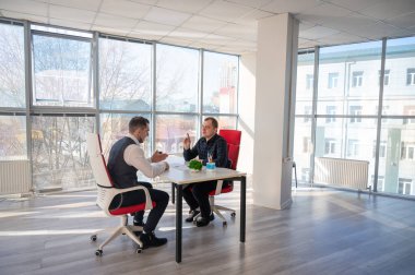 İki beyaz adam bir iş toplantısında iletişim kuruyor.