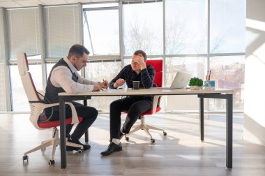 Bir ofiste pazarlık yapan iki beyaz adam.