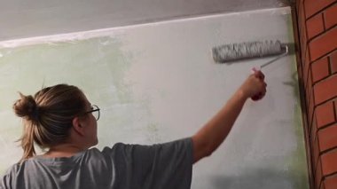 Kafkas kadın silindirle duvar boyuyor.