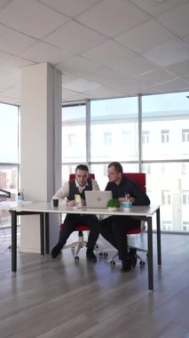 İki beyaz adam bir masada oturup iş tartışıyorlar.