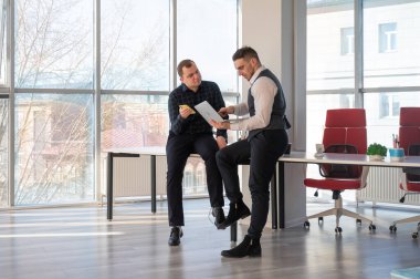 Ofiste iş tartışan iki beyaz adam. İşitme cihazı olan bir iş adamı.