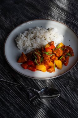 Tatlı ve ekşi soslu domuz eti ve tabakta haşlanmış pirinç.