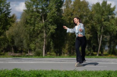 Beyaz kadın parkta paten kayıyor.