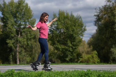 Beyaz kadın parkta paten kayıyor.