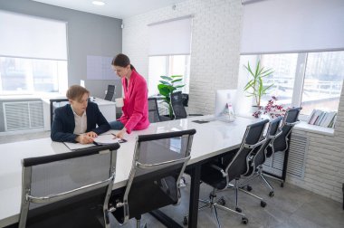 Beyaz kadın astlarına talimat veriyor.