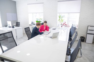 Kadın ve erkek ofiste otururken konuşuyorlar.