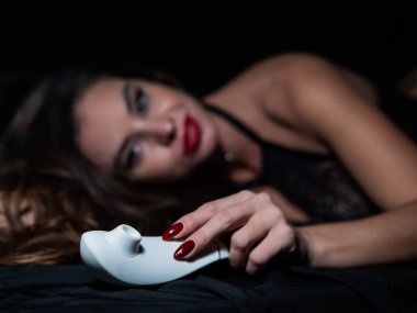 Dantelli iç çamaşırlı bir kadın beyaz klitoral vakum uyarıcısı tutuyor.