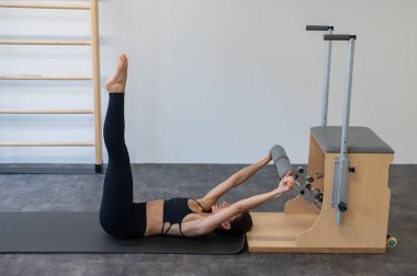 Beyaz kadın klasik sandalyede pilates yapıyor.