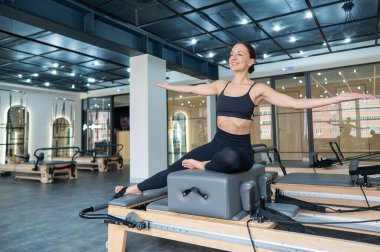 Kafkasyalı kadın yenilikçi makinede yan büküş yapıyor.