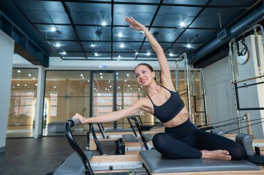 Kafkasyalı kadın yenilikçi makinede yan büküş yapıyor.