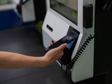 Bir kadın kendini kontrol ederken akıllı telefonuyla ödeme yapar.