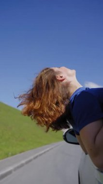 Mutlu beyaz kadın araba kullanırken pencereden sarkıyor.