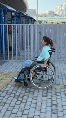 Tekerlekli sandalyedeki bir kadın dokunmaya duyarlı körler için yardım düğmesi kullanır..