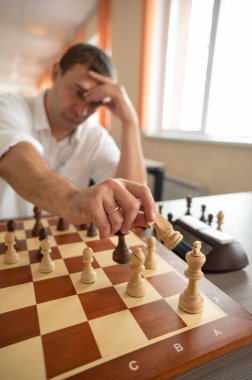 Orta yaşlı beyaz adam satranç oynuyor.