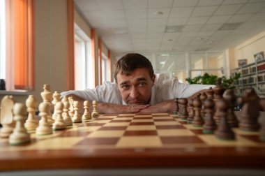 Orta yaşlı beyaz adam satranç oynuyor.