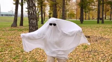 Bir sonbahar ormanının arka planında hayalet kostümlü bir kadın. Cadılar Bayramı kostümü