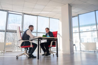 İki beyaz adam bir iş toplantısında iletişim kuruyor.