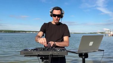 Beyaz adam plajda DJ olarak çalışıyor.