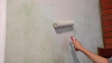 Kafkas kadın silindirle duvar boyuyor.