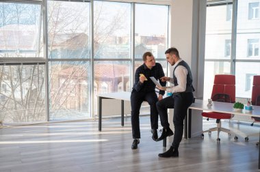 Ofiste iş tartışan iki beyaz adam. İşitme cihazı olan bir iş adamı.