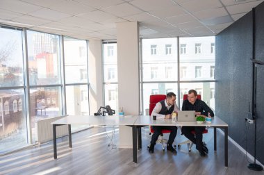 İki beyaz adam bir masada oturup iş tartışıyorlar.