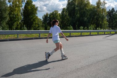 Beyaz şortlu kadın paten kayıyor.