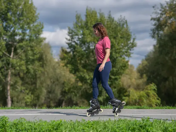 Beyaz kadın parkta paten kayıyor.