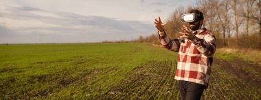 Gün batımında sanal gerçeklik gözlükleriyle buğday tarlasında duran genç adam.