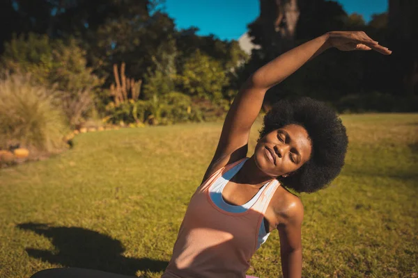 African american woman practicing yoga in garden. staying at home in isolation during quarantine lockdown.