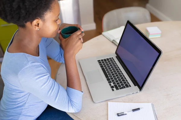 非洲裔美国妇女在家里工作 使用笔记本电脑 屏幕上有复制空间 喝咖啡 隔离检疫期间单独呆在家里 — 图库照片