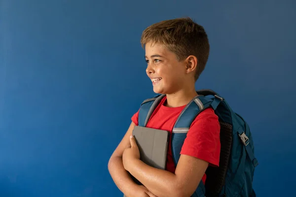 Sırt Çantalı Dijital Tabletli Beyaz Çocuk Mavi Arka Planda Duruyor — Stok fotoğraf
