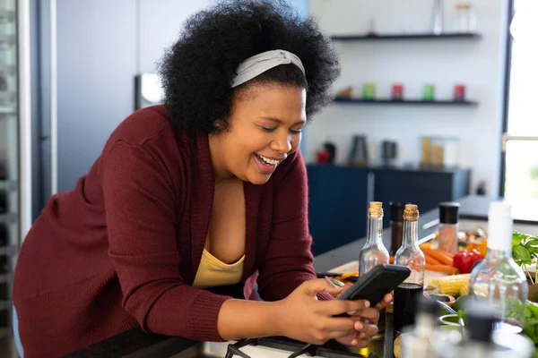 Mutlu Afrikalı Amerikalı Kadın Akıllı Telefon Kullanıyor Mutfakta Yemek Hazırlıyor — Stok fotoğraf