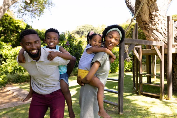 Mutlu Afro Amerikan Ebeveynler Parkta Dikilirken Oğullarını Kızlarını Sırtında Taşıyorlar — Stok fotoğraf