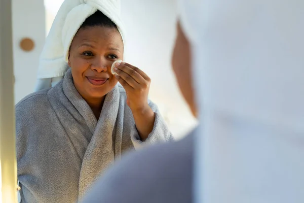 幸せプラスサイズアフリカ系アメリカ人女性のバスルームミラーを探して綿パッドで顔をクレンジング セルフケア 健康と美しさ 身体の包容力とライフスタイル 変わらない — ストック写真