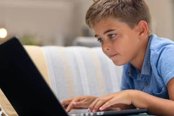 Caucasiano Menino Sério Usando Laptop Enquanto Deitado Sofá Sala Estar — Fotografia de Stock