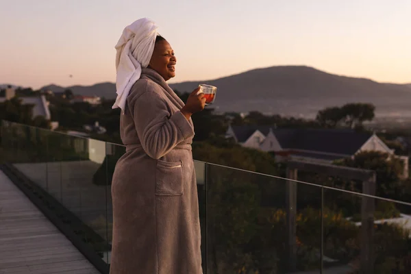 Mutlu Cüsseli Afro Amerikan Kadın Kafasında Havluyla Bornoz Balkonda Çay — Stok fotoğraf