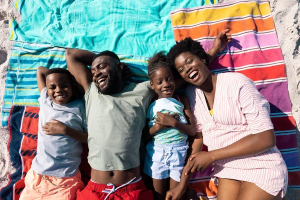 ビーチでタオルに横になっている間に笑うアフリカ系アメリカ人の両親と子供たちの高い角度のビュー 変更されていない 一緒に 子供時代 ピクニック リラックス 楽しさと夏のコンセプト — ストック写真