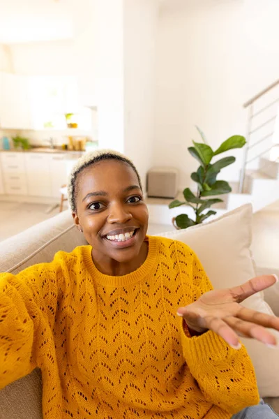 在客厅的沙发上放松的同时 微笑着一个有着短发的非洲裔美国年轻女子 复制空间 生活方式和家庭观念 — 图库照片