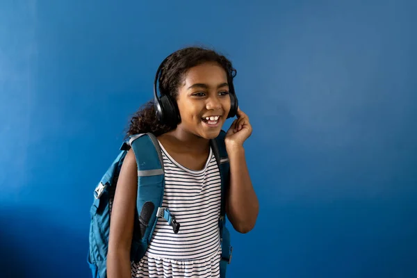 Ευτυχισμένος Biracial Μαθήτρια Φορώντας Ακουστικά Ακούγοντας Μουσική Μπλε Φόντο Χώρο — Φωτογραφία Αρχείου