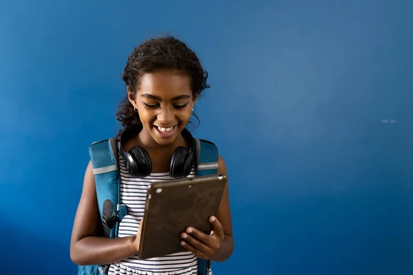 快乐的学校女生带着耳机使用平板电脑 带着蓝色背景和复制空间微笑 学校和技术 — 图库照片