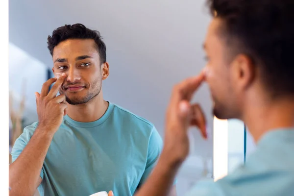 Gülümseyen Melez Adam Banyo Aynasında Kendine Bakıyor Yüz Kremi Sürüyor — Stok fotoğraf