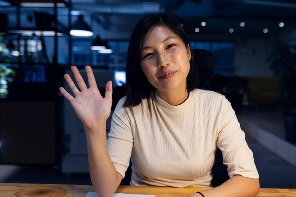 Glædelig Asiatisk Forretningskvinde Der Sidder Vinker Laver Videoopkald Arbejder Sent - Stock-foto