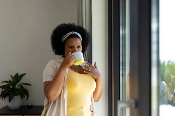 Thoughtful Size African American Woman Looking Out Window Drinking Coffee — Stock Photo, Image
